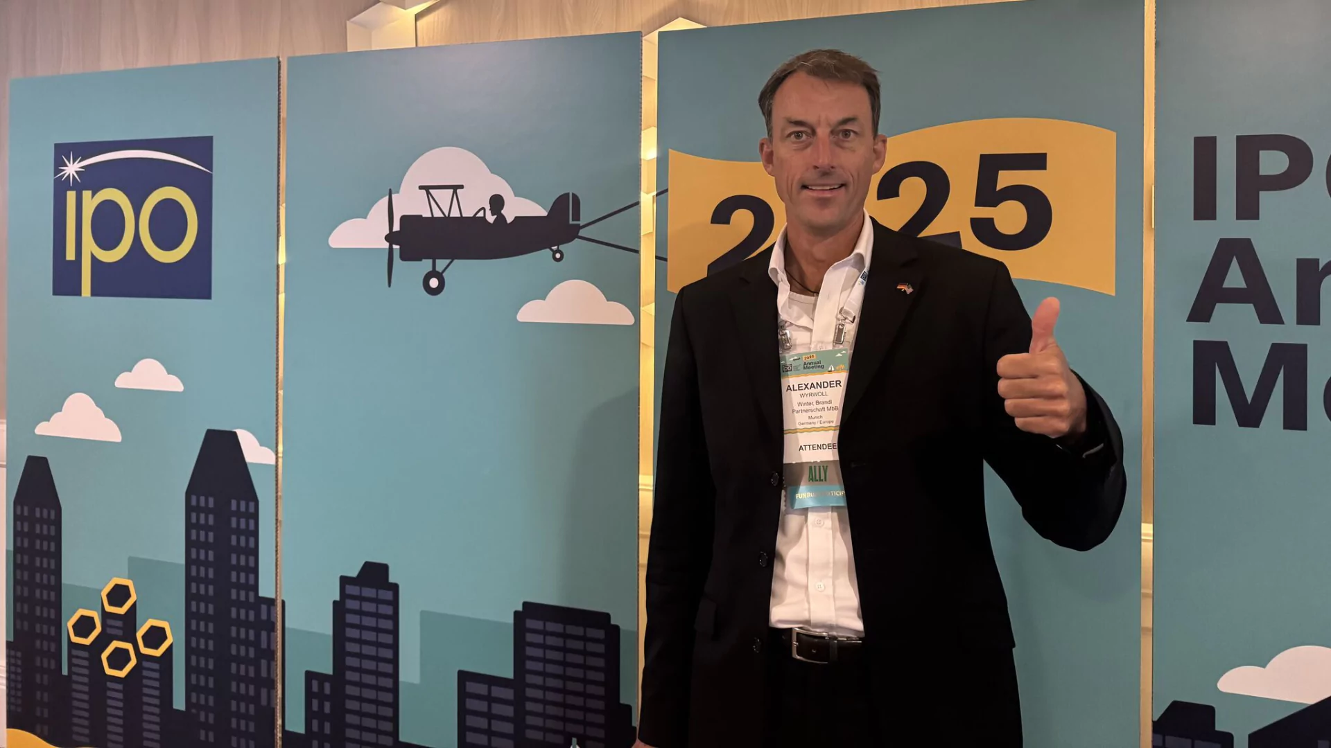 Dr. Alexander Wyrwoll vor der Logo-Wand beim IPO Jahresmeeting 2025